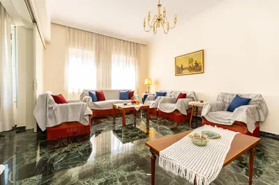 a living room with chairs and tables and a chandelier at Evridiki's House Central Chania in Chania Town