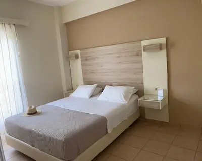 a bedroom with a large bed with a wooden headboard at Poseidon Studios & Apartments in Palaiochóra