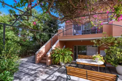 a house with a table and benches in front of it at Poseidon Studios & Apartments in Palaiochóra