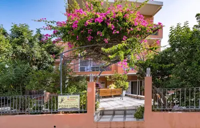 a building with a tree with pink flowers on it at Poseidon Studios & Apartments in Palaiochóra