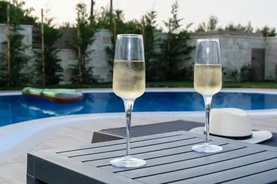 two glasses of champagne sitting on a table next to a pool at Villa Thalia in Stalos