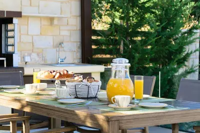 a wooden table with food and a jug of orange juice at Villa Thalia in Stalos