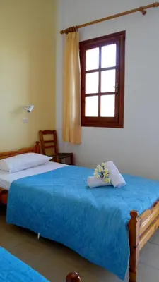 a bedroom with a bed with blue sheets and a window at Katerina Palaiochora in Palaiochóra
