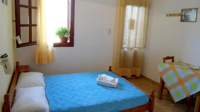a small bedroom with a blue bed and a window at Katerina Palaiochora in Palaiochóra