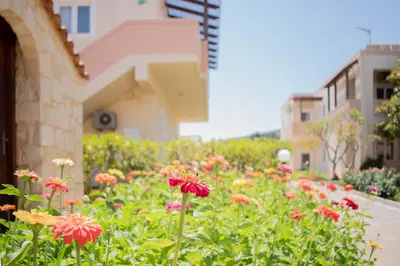 a garden with red flowers in front of a building at Dimitra & Evdokia Hotel in Agia Marina Nea Kydonias