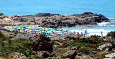 a group of people on a beach with umbrellas at Estia in Plátanos