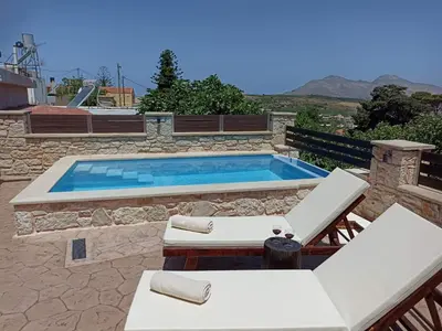 a swimming pool with two lounge chairs and a table at Estia in Plátanos