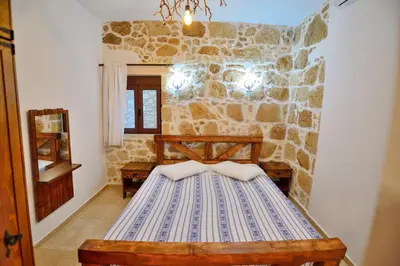 a bedroom with a bed in a stone wall at Nemesis in Plátanos