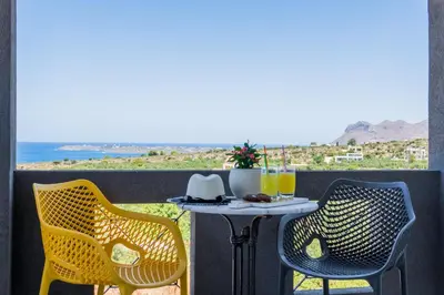 a table and chairs on a balcony with a view at Talos Luxury Suites in Kounoupidhianá
