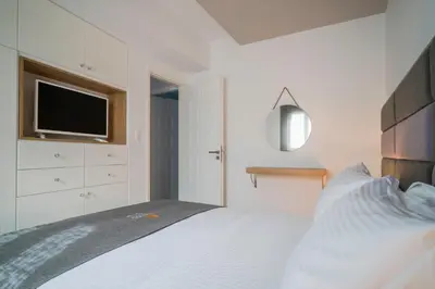 a bedroom with a white bed and a tv at Talos Luxury Suites in Kounoupidhianá
