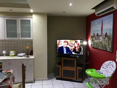 a living room with a flat screen tv on a wall at Steps to Nea Chora beach Angela apt ,10min to town in Chania Town