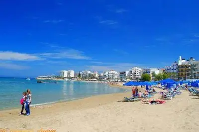 a group of people on a beach with blue umbrellas at Steps to Nea Chora beach Angela apt ,10min to town in Chania Town