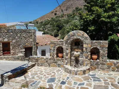 a stone building with a stone oven in front of a mountain at Dream House in Perivólia