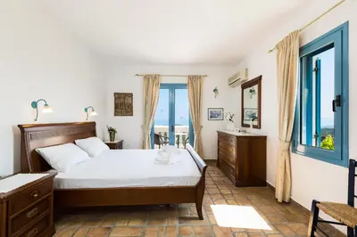 a bedroom with a bed and a large window at Villa Ariadne in Stalos