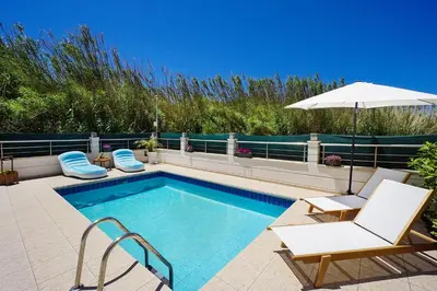 a swimming pool with two chairs and an umbrella at Geas House Thalassa in Kolymvari
