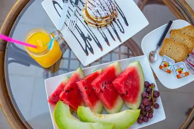 a plate of fruit on a table with a drink at Geas House Thalassa in Kolymvari
