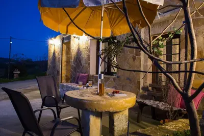 a stone table with chairs and an umbrella at Μylos in Kissamos