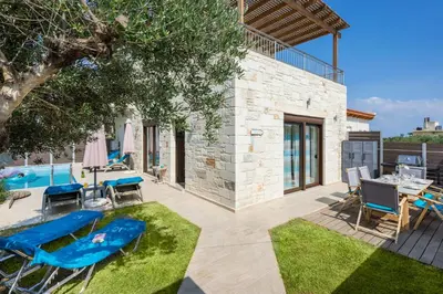 a patio with a table and chairs and a pool at Villa Rebecca in Agia Marina Nea Kydonias
