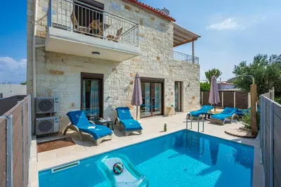 a swimming pool with blue chairs and a house at Villa Rebecca in Agia Marina Nea Kydonias