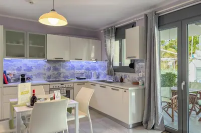 a kitchen with white cabinets and a table and chairs at Alisahni Villa & Suite in Kato Daratso