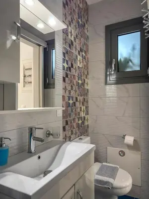 a bathroom with a sink and a toilet and a mirror at Alisahni Villa & Suite in Kato Daratso