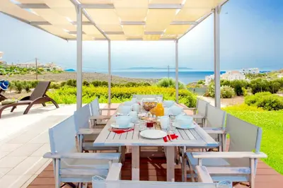 a table on a patio with a view of the ocean at Luxury Villa Stella with private swimming pool in Tersanas