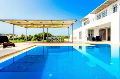 an outdoor swimming pool with a pergola next to a house at Luxury Villa Stella with private swimming pool in Tersanas