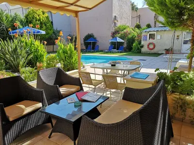 a patio with tables and chairs and a pool at Nicolas Studios & Apartments in Agia Marina Nea Kydonias