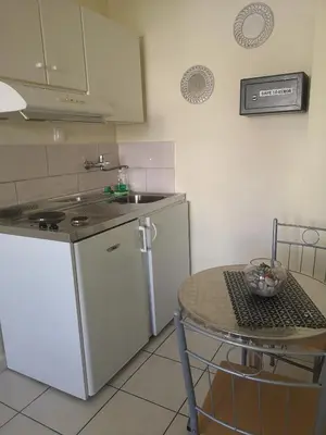 a kitchen with a table and a sink and a refrigerator at Nicolas Studios & Apartments in Agia Marina Nea Kydonias