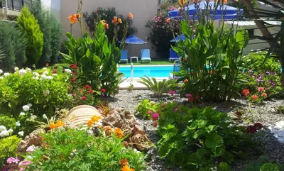 a garden with flowers and a swimming pool at Nicolas Studios & Apartments in Agia Marina Nea Kydonias
