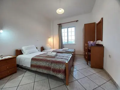 a bedroom with two beds and a desk and a window at Babis Apartments in Plataniás