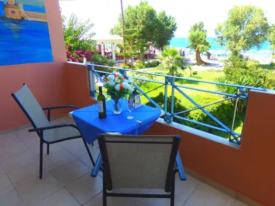 a table with a vase of flowers on a balcony at Katerina Seaside Studios in Plataniás