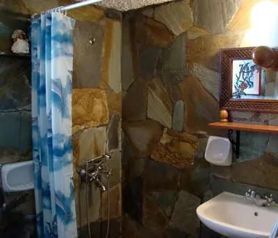 a stone bathroom with a shower and a sink at Drapanias BeachFront Apartments - Marinakis in Kissamos