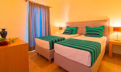a bedroom with two beds with green and white pillows at Oreia in Palaiochóra