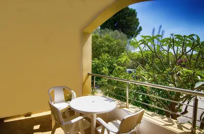 a white table and chairs on a balcony with a window at Hotel Aghas Paleochora in Palaiochóra