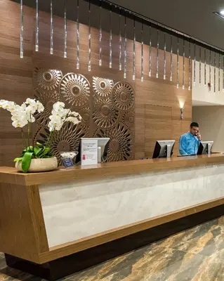 a man sitting at a reception desk in a lobby at Solimar Aquamarine Resort in Gerani Chanion