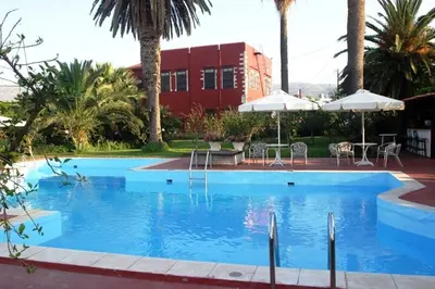 a large blue swimming pool with chairs and umbrellas at Oasis Guesthouse in Chania Town