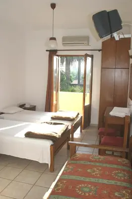 a bedroom with two beds and a window and a tv at Oasis Guesthouse in Chania Town