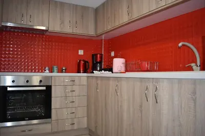 a kitchen with wooden cabinets and a red wall at Rodoula Luxury Αpartment 3 in Chania Town