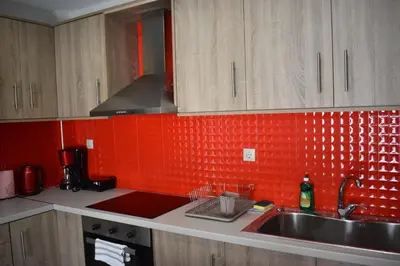 a kitchen with a sink and a red tiled wall at Rodoula Luxury Αpartment 4 in Chania Town
