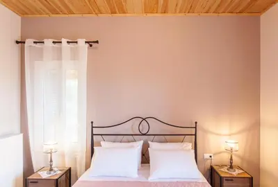 a bedroom with a bed with white pillows and a window at Villa Vendema in Arménoi