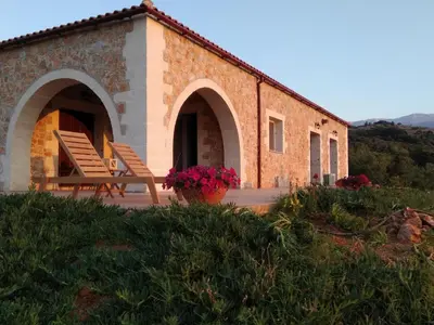a building with two chairs and flowers in front of it at Villa Vendema in Arménoi