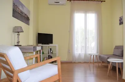 a living room with a television and a chair and a couch at Central House with Quiet Garden in Kissamos