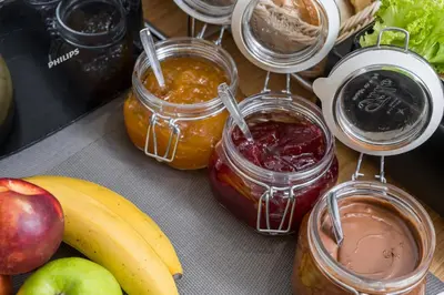 a table with jars of jam next to fruits and vegetables at Casa D'Irene Deluxe Hotel in Falasarna