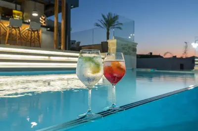 two wine glasses sitting next to a swimming pool at Casa D'Irene Deluxe Hotel in Falasarna