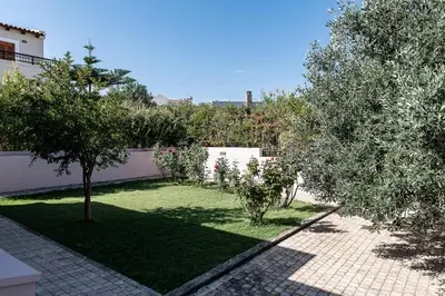 a garden with olive trees and a white fence at Lila hill house in Stalos