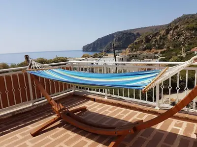 a hammock on top of a balcony with the ocean at Marinakis Sea View Studios in Sougia