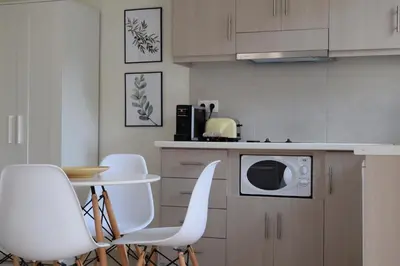 a kitchen with white chairs and a microwave at Aelia Apartments in Chania Town