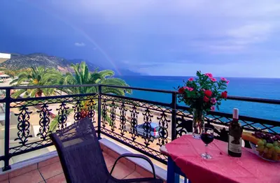 a balcony with a table with flowers and a view of the ocean at Scorpios Family Rooms in Palaiochóra