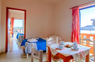 a living room with a table and a dining room at Scorpios Family Rooms in Palaiochóra